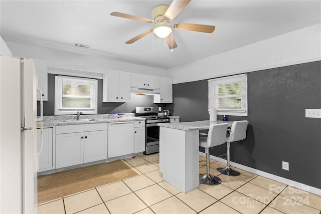 kitchen featuring white cabinets, sink, ceiling fan, a breakfast bar, and white appliances