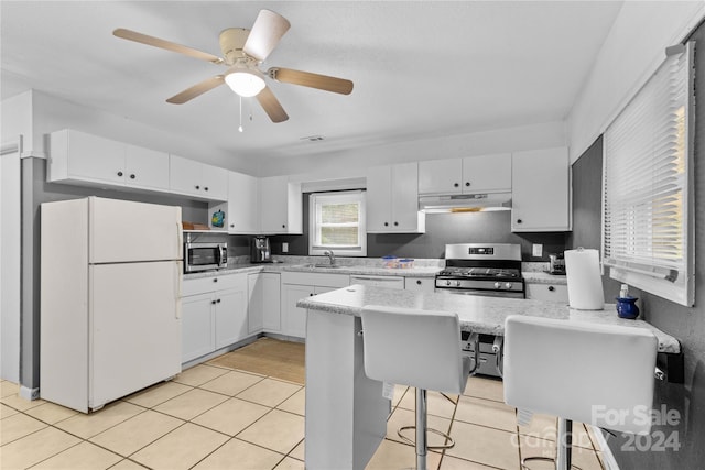 kitchen featuring light hardwood / wood-style floors, white cabinetry, a breakfast bar, appliances with stainless steel finishes, and ceiling fan