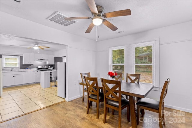 dining room featuring ceiling fan, sink, a healthy amount of sunlight, and light hardwood / wood-style flooring