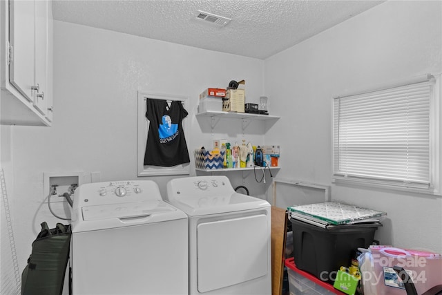 clothes washing area with cabinets, independent washer and dryer, and a textured ceiling