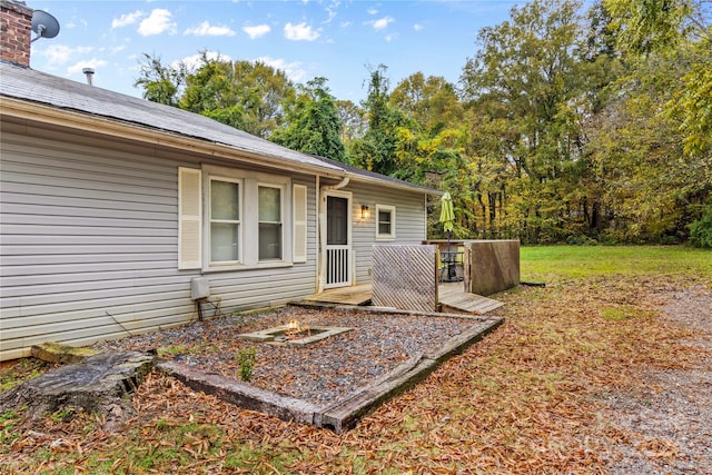 view of exterior entry featuring a lawn and a wooden deck