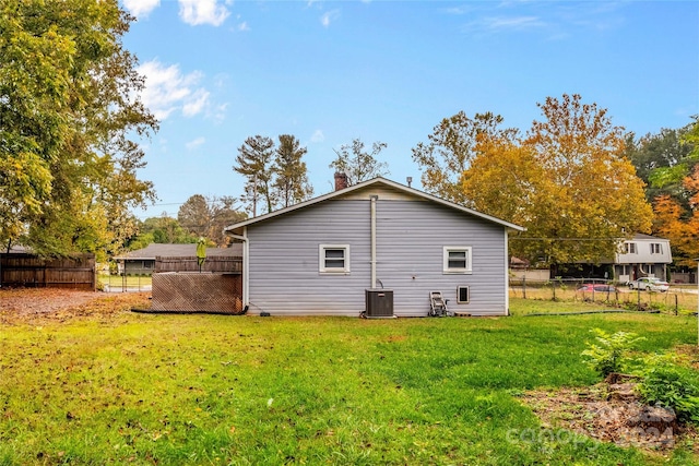 rear view of house with central air condition unit and a yard