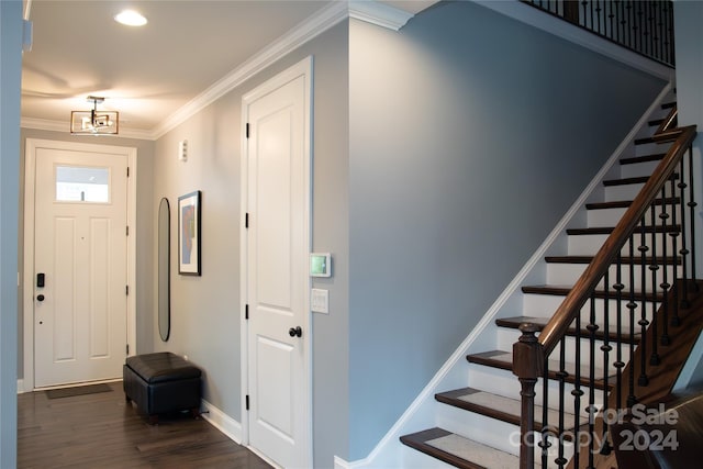 entryway with a notable chandelier, dark hardwood / wood-style flooring, and ornamental molding