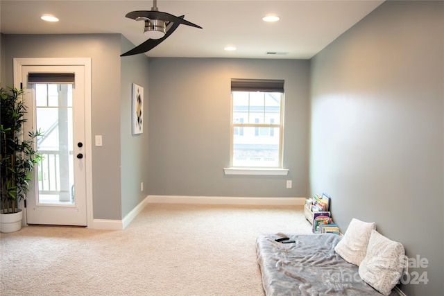 living area featuring light colored carpet and ceiling fan