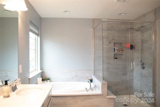 bathroom featuring vanity, plenty of natural light, and plus walk in shower