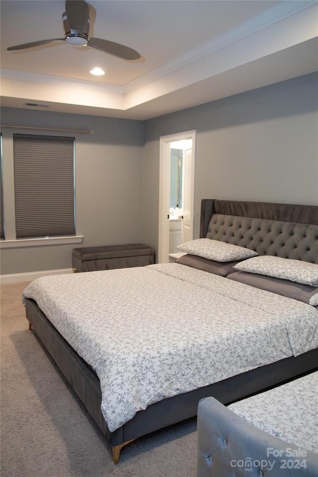 carpeted bedroom with ceiling fan, ensuite bath, a raised ceiling, and crown molding