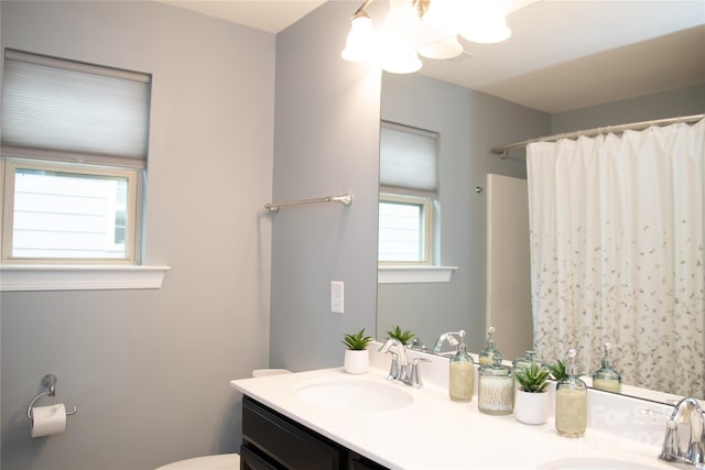 bathroom with walk in shower, vanity, and toilet