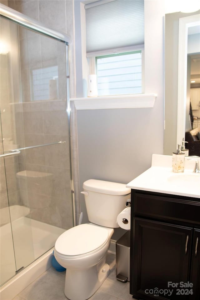 bathroom with walk in shower, tile patterned flooring, vanity, and toilet