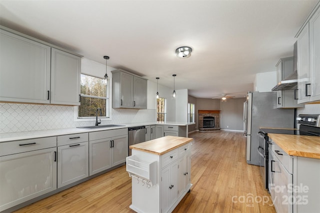 kitchen featuring butcher block countertops, pendant lighting, gray cabinetry, and stainless steel appliances