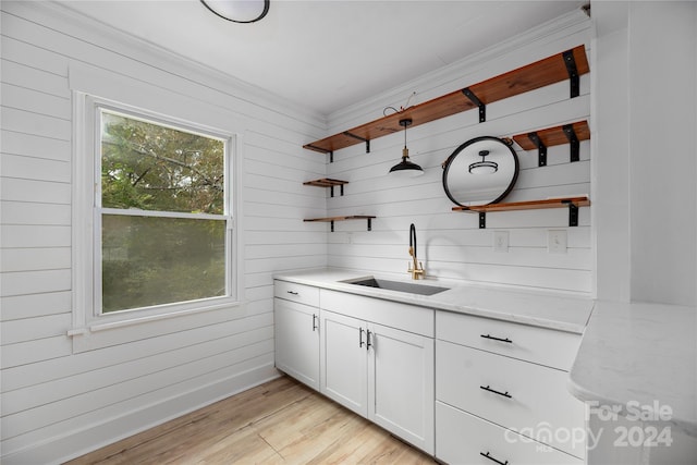 bar featuring white cabinetry, light hardwood / wood-style flooring, sink, and light stone countertops