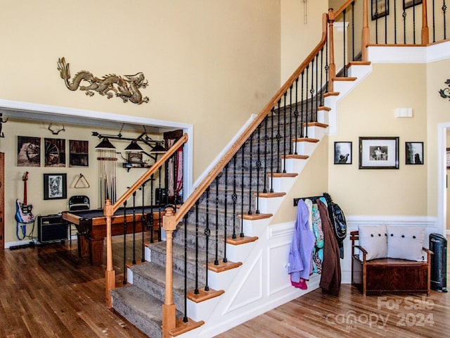 stairs featuring hardwood / wood-style floors and a towering ceiling