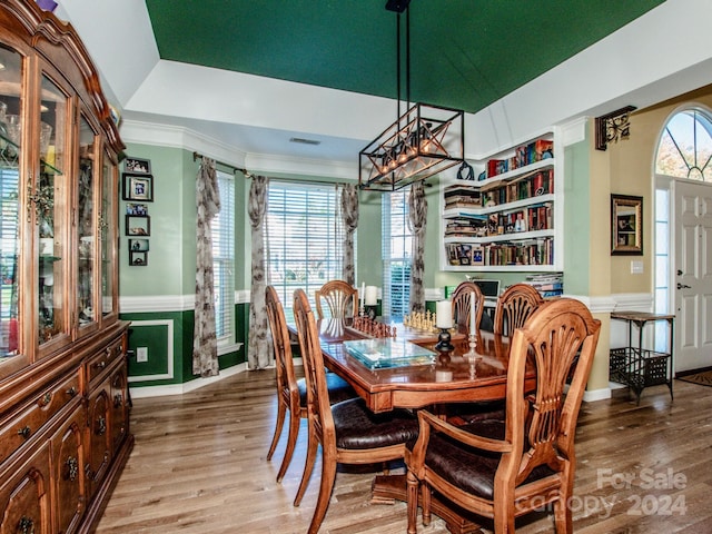 dining space with light wood-type flooring and a tray ceiling