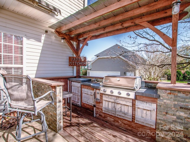 wooden terrace featuring grilling area, sink, and exterior kitchen