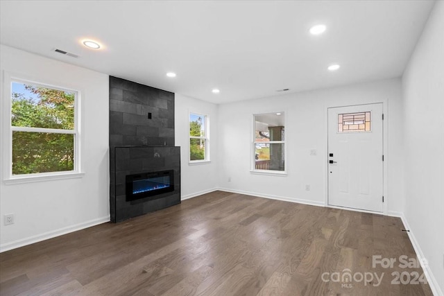 unfurnished living room featuring a fireplace, a healthy amount of sunlight, and dark hardwood / wood-style floors