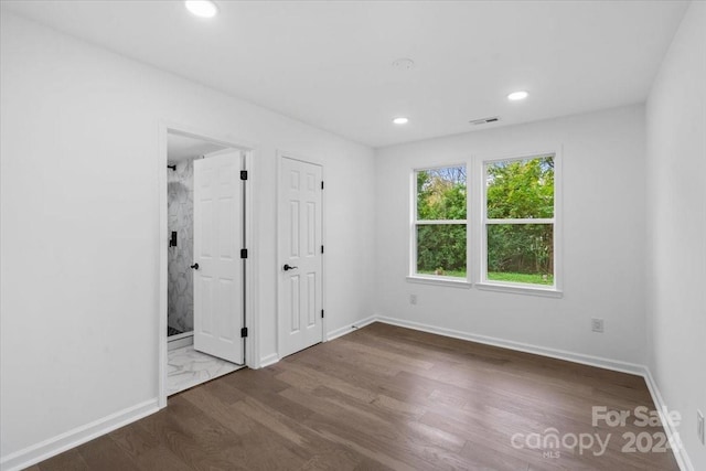 unfurnished bedroom with dark wood-type flooring and ensuite bath