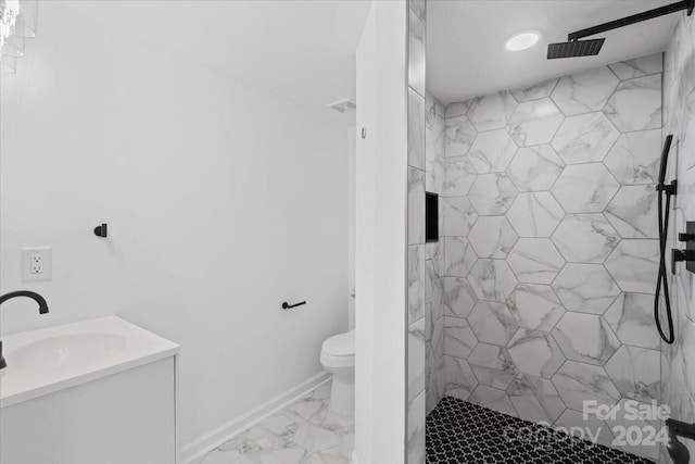 bathroom featuring a tile shower, vanity, and toilet