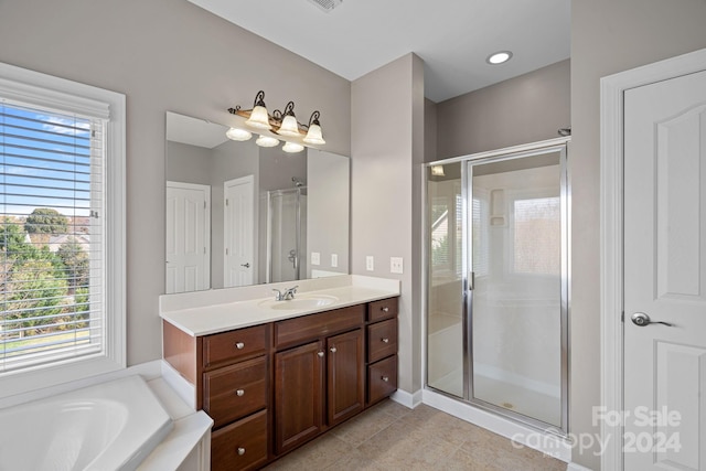 bathroom with a wealth of natural light, tile patterned flooring, vanity, and shower with separate bathtub