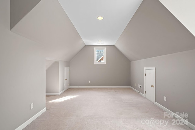 additional living space featuring light colored carpet and lofted ceiling