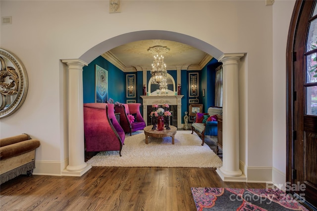 interior space with a notable chandelier, crown molding, ornate columns, and hardwood / wood-style floors