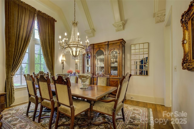 dining area featuring a towering ceiling, a chandelier, and hardwood / wood-style flooring