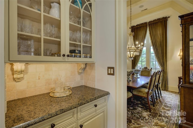 bar with decorative backsplash, light stone countertops, and pendant lighting