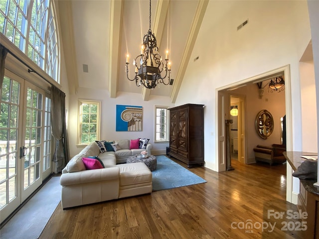 living room featuring dark hardwood / wood-style flooring, beam ceiling, a towering ceiling, and french doors