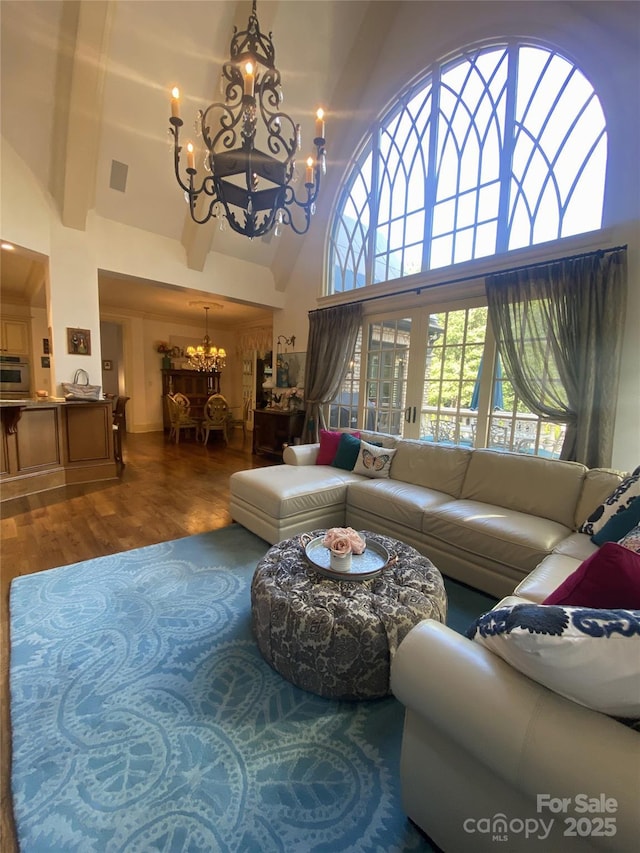 living room with a high ceiling, a chandelier, and hardwood / wood-style flooring