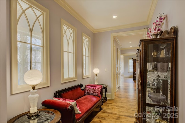 sitting room with ornamental molding and light wood-type flooring