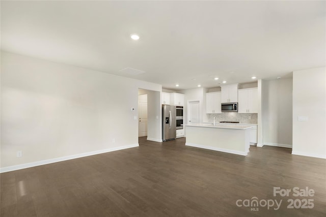 unfurnished living room featuring sink and dark wood-type flooring