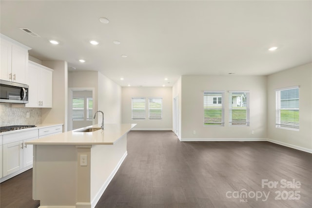 kitchen with white cabinetry, sink, stainless steel appliances, and a center island with sink