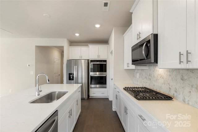 kitchen with sink, tasteful backsplash, light stone counters, white cabinetry, and stainless steel appliances