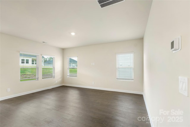 empty room featuring plenty of natural light and dark hardwood / wood-style floors