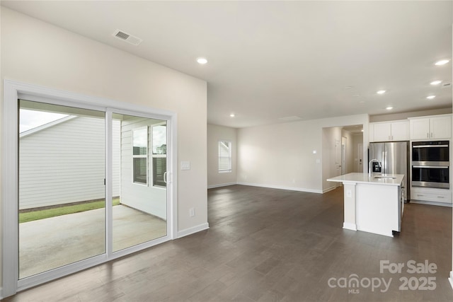 kitchen with a kitchen island with sink, sink, dark hardwood / wood-style flooring, white cabinetry, and stainless steel appliances