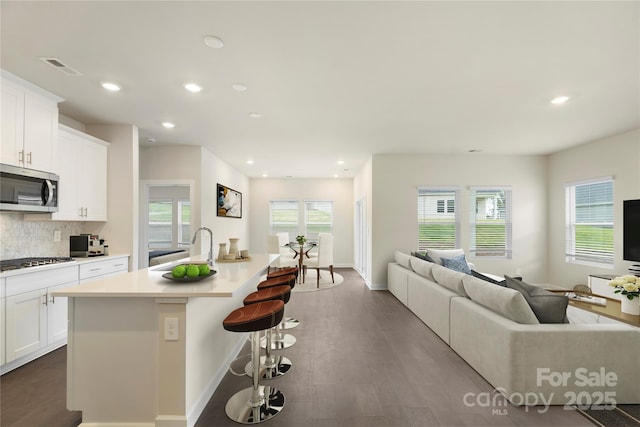 kitchen featuring sink, an island with sink, a kitchen bar, white cabinetry, and stainless steel appliances