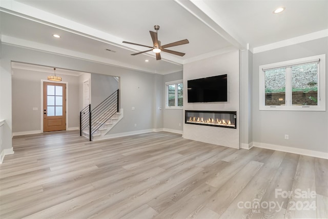 unfurnished living room with plenty of natural light, light hardwood / wood-style floors, and ornamental molding