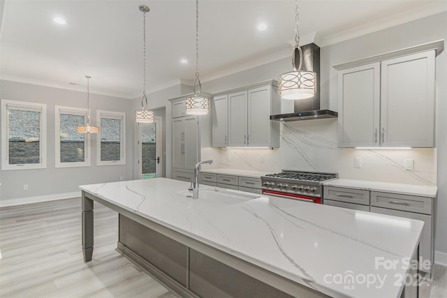 kitchen with pendant lighting, stainless steel stove, wall chimney exhaust hood, and sink