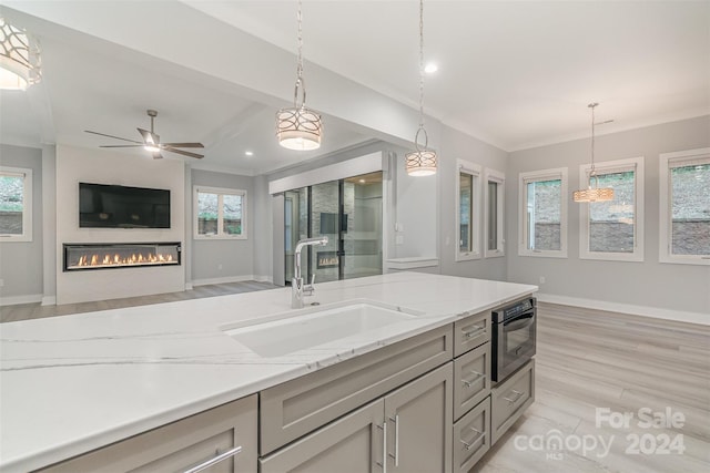 kitchen with decorative light fixtures, sink, a wealth of natural light, and light hardwood / wood-style flooring