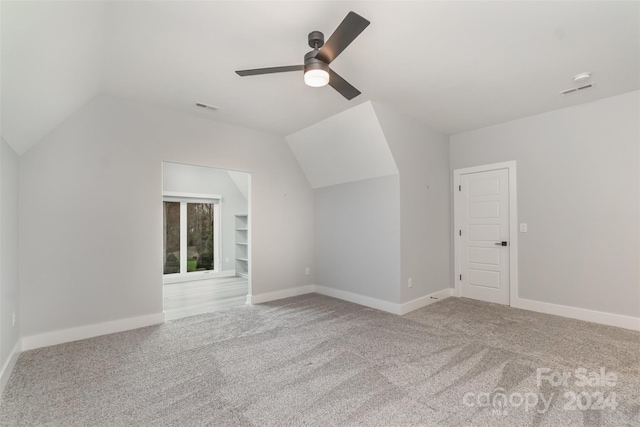 additional living space featuring carpet flooring, built in shelves, vaulted ceiling, and ceiling fan