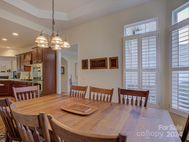 dining area with ornamental molding, a chandelier, and a raised ceiling