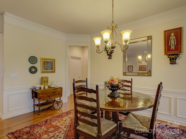 dining area featuring hardwood / wood-style floors, a notable chandelier, and crown molding