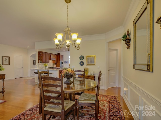 dining room with a chandelier, light wood-type flooring, and ornamental molding