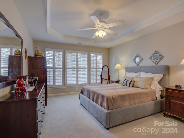 carpeted bedroom featuring ceiling fan and a raised ceiling