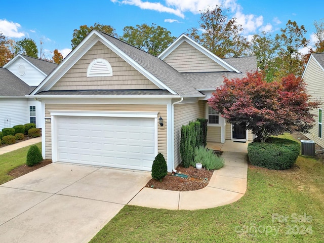 view of front of home with a garage, cooling unit, and a front lawn