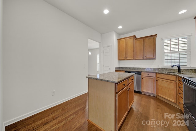 kitchen featuring wood-type flooring, stainless steel appliances, dark stone counters, sink, and a center island