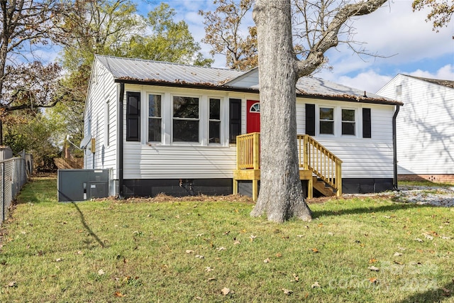 view of front of home with cooling unit and a front yard