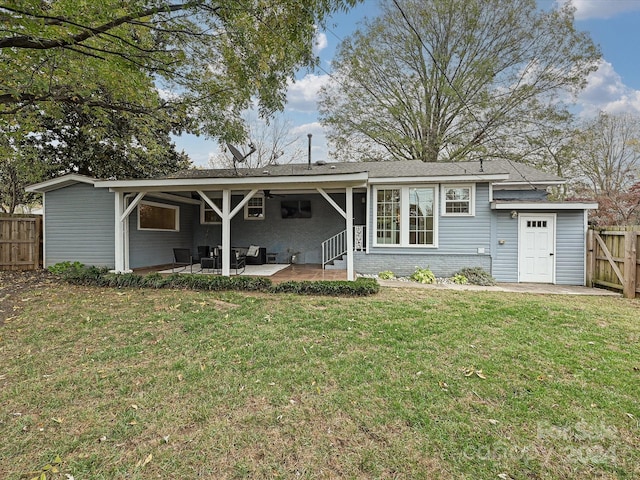 rear view of property with a lawn, ceiling fan, and a patio