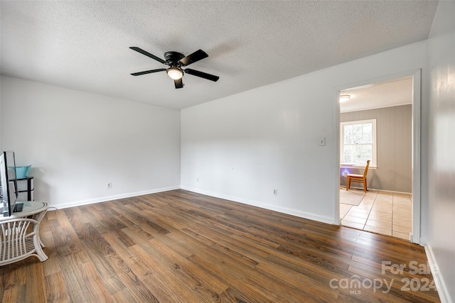 empty room with dark wood-type flooring, ceiling fan, and a textured ceiling