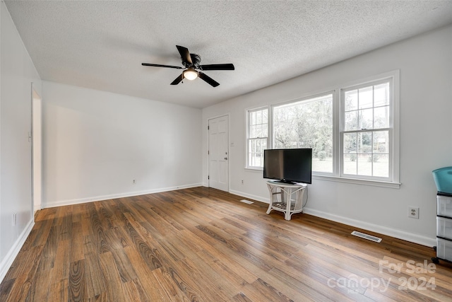 unfurnished living room featuring a textured ceiling, hardwood / wood-style floors, and ceiling fan