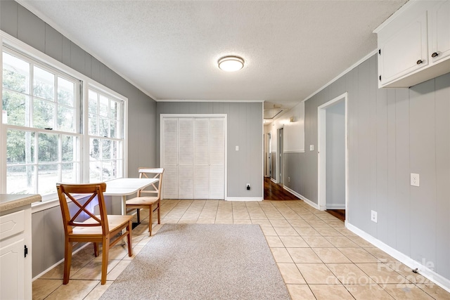 tiled dining area featuring a textured ceiling, wooden walls, and crown molding