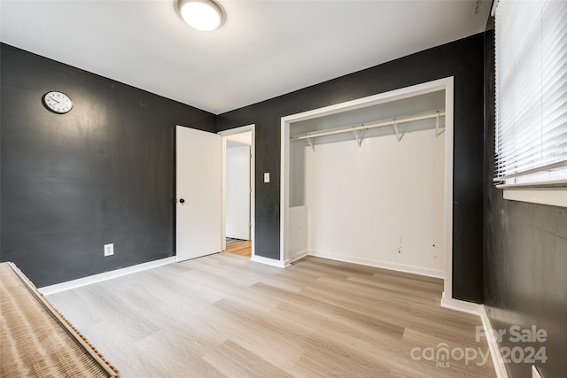 unfurnished bedroom with a closet and light hardwood / wood-style floors